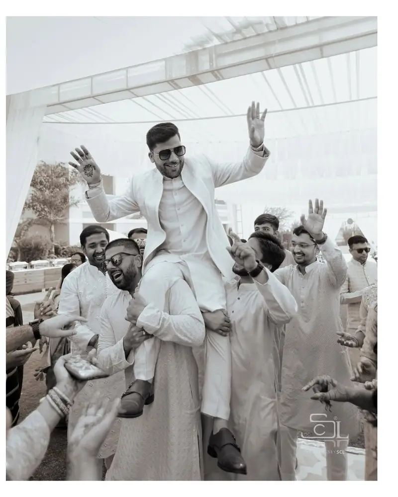 A groom lifted onto his friends' shoulders during the baraat