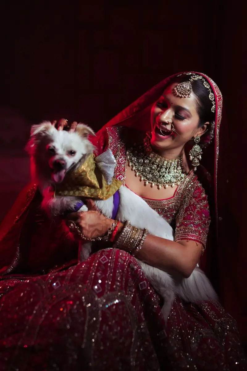 A bride in a red lehenga hugging her dog before the ceremony